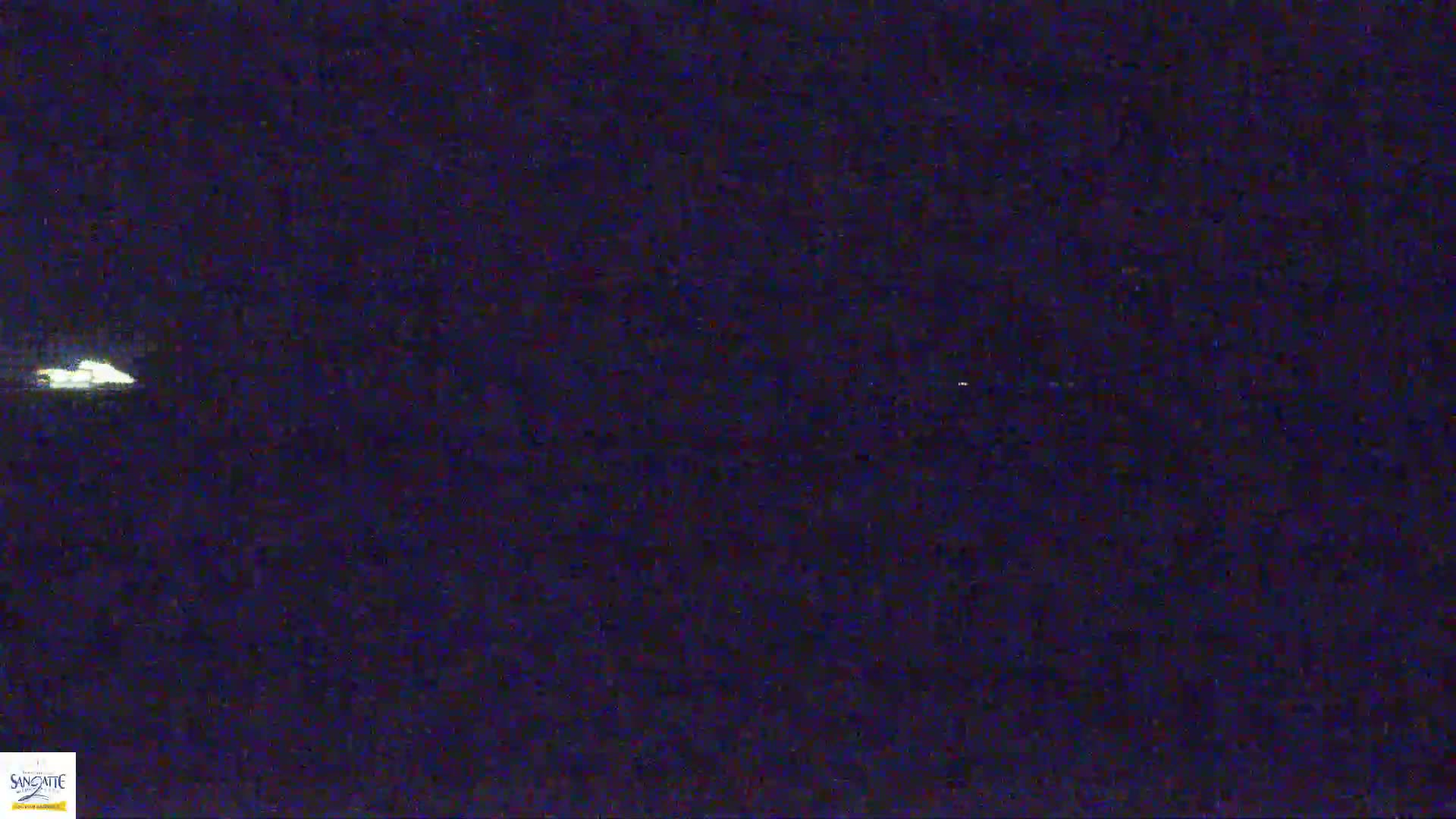 A dimly lit, dark nighttime scene shows a small, bright light in the distance.