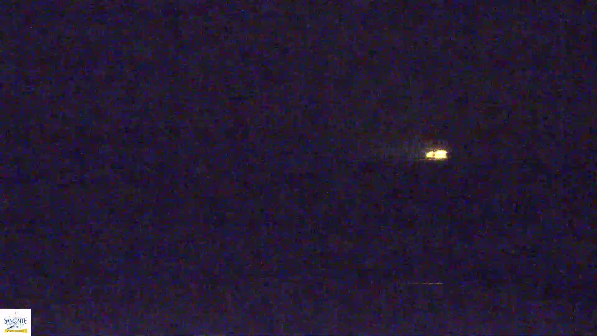 A small, distant light source is visible in a dark, nighttime sky.