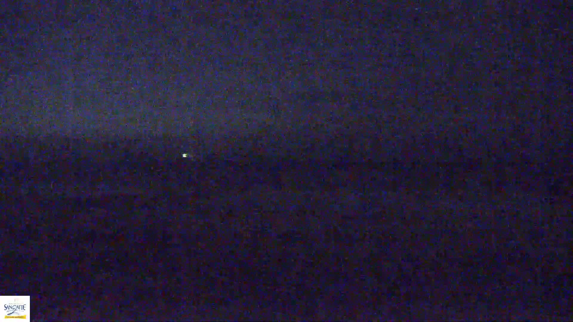 A dark, nighttime landscape is visible, with a single, distant light source.