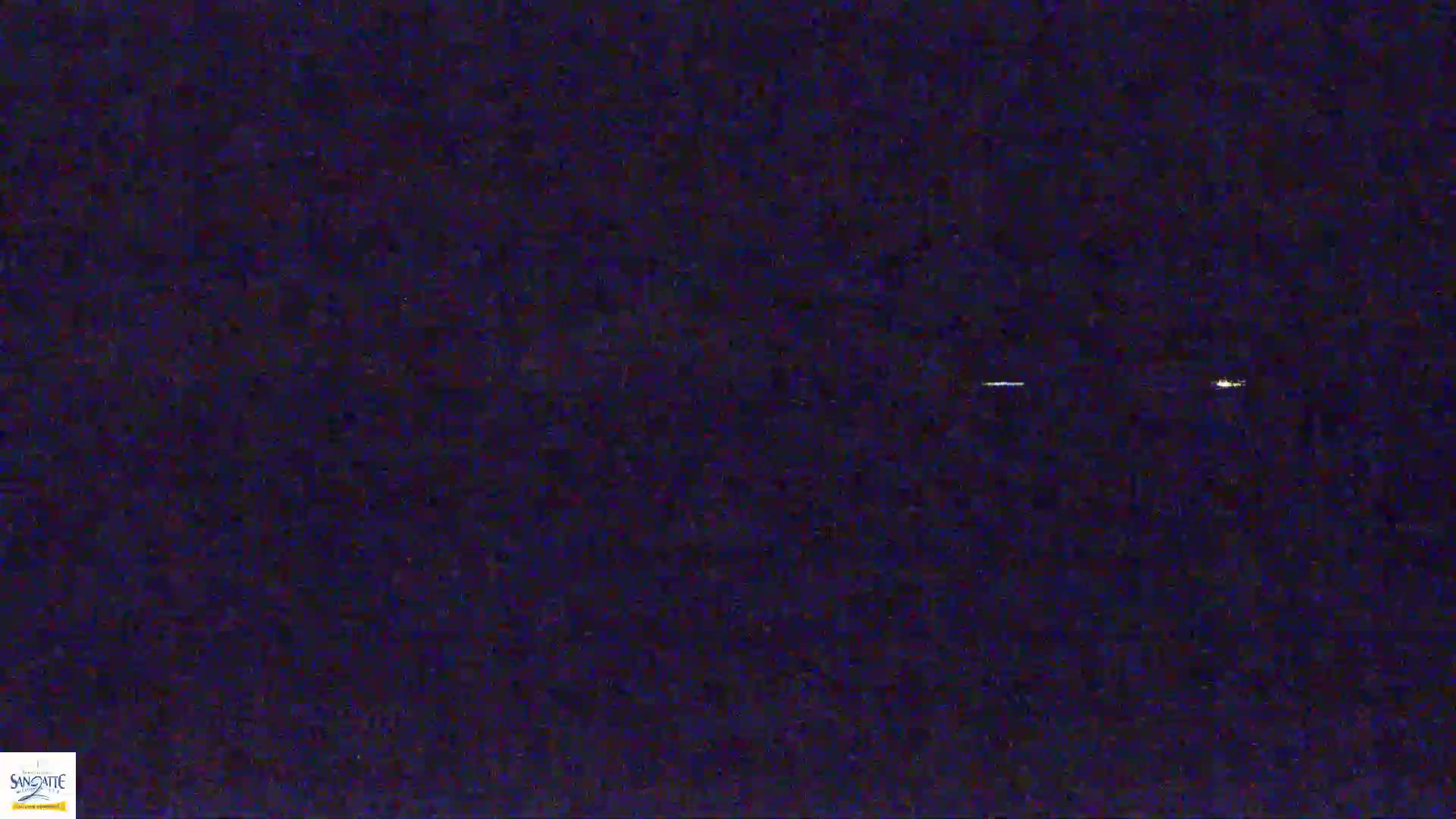 A dark nighttime scene shows a few faint, distant lights.
