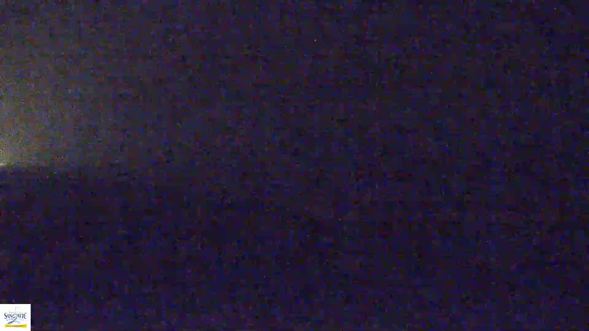 A nighttime image shows a dark, possibly cloudy sky above a dark, indistinct landscape.