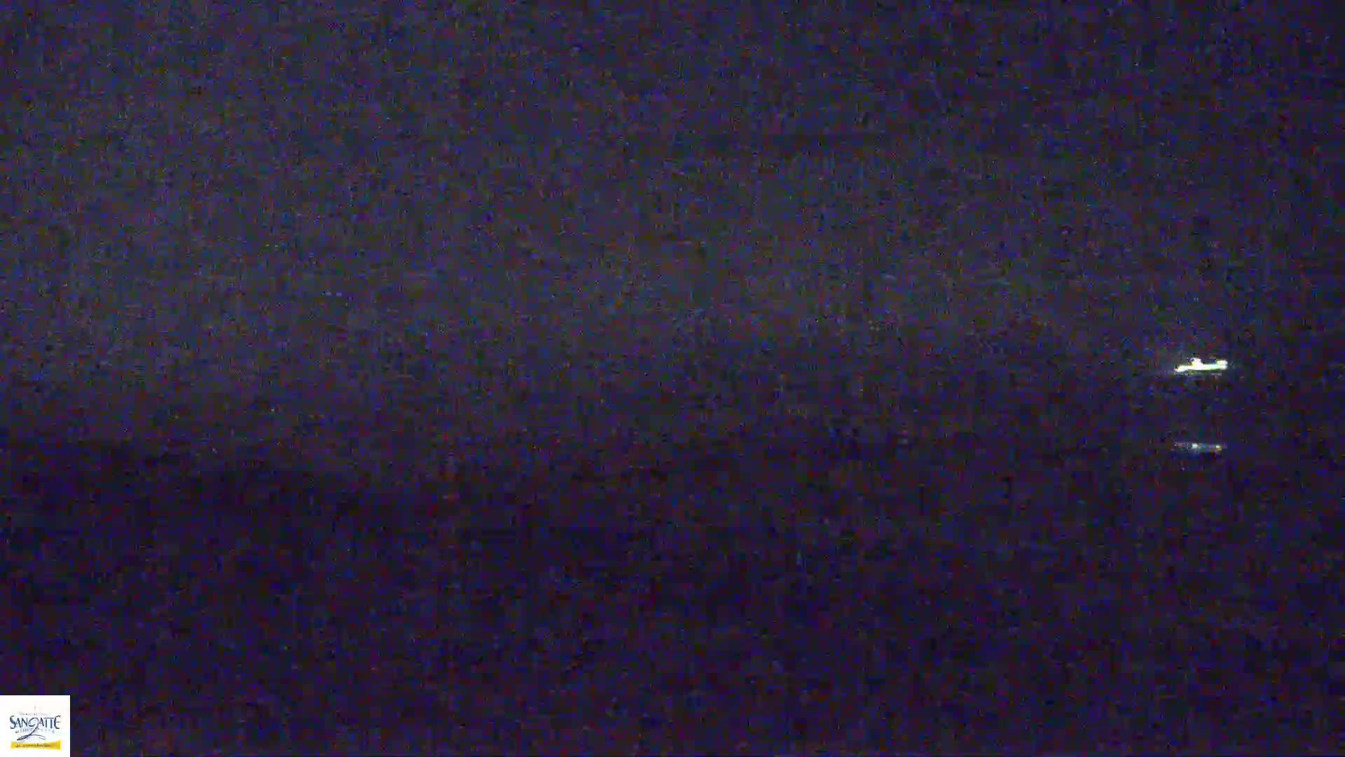 Two faint lights are visible on a dark, nighttime horizon.
