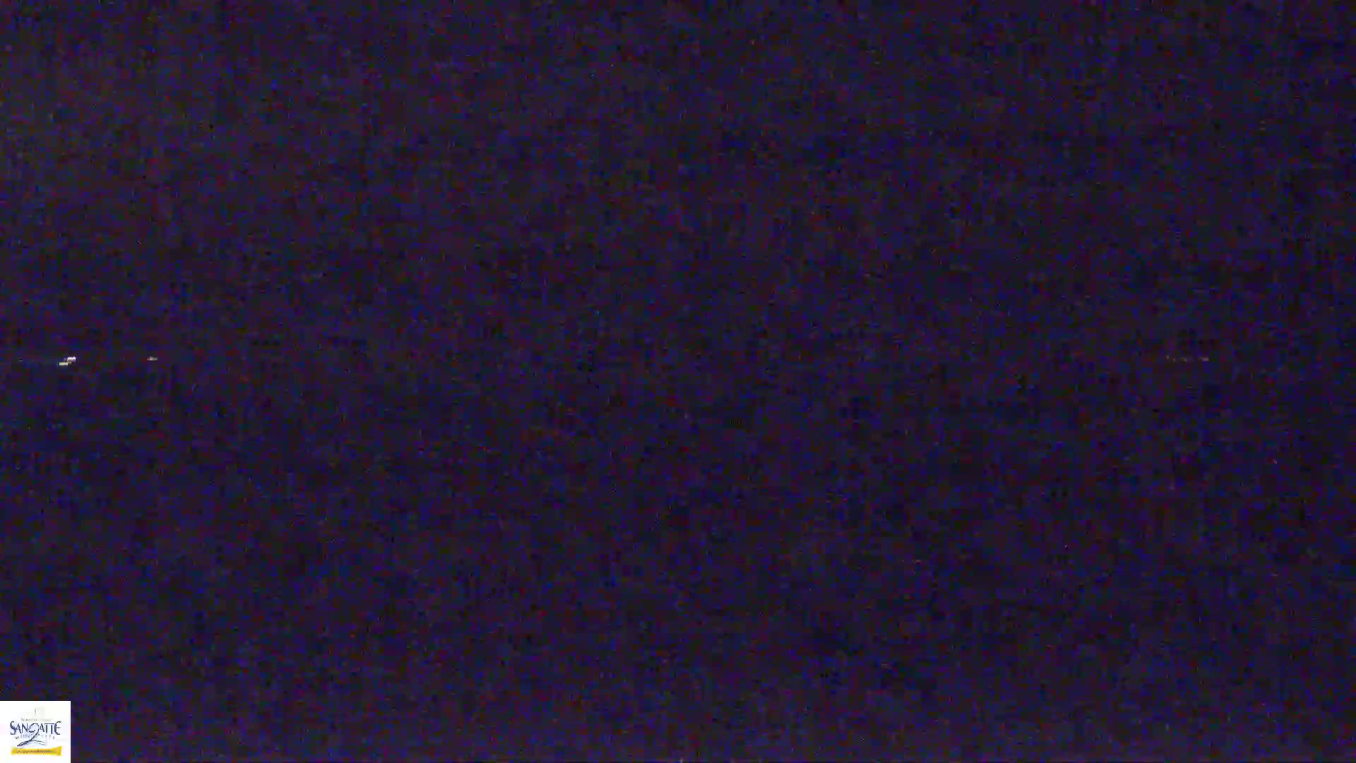 A dark, possibly nighttime scene shows a few faint lights in the distance.