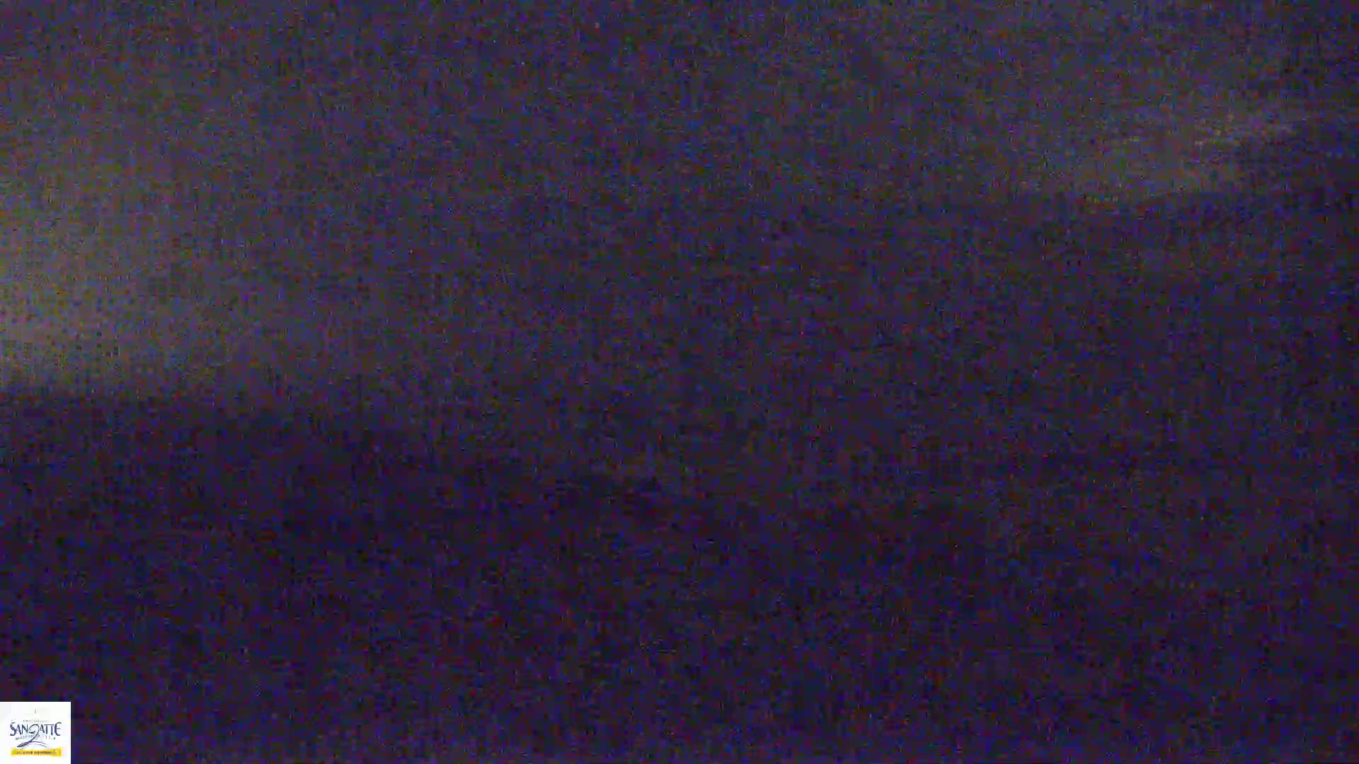 A dark, blurry image of a landscape under a night sky with a slightly brighter horizon.