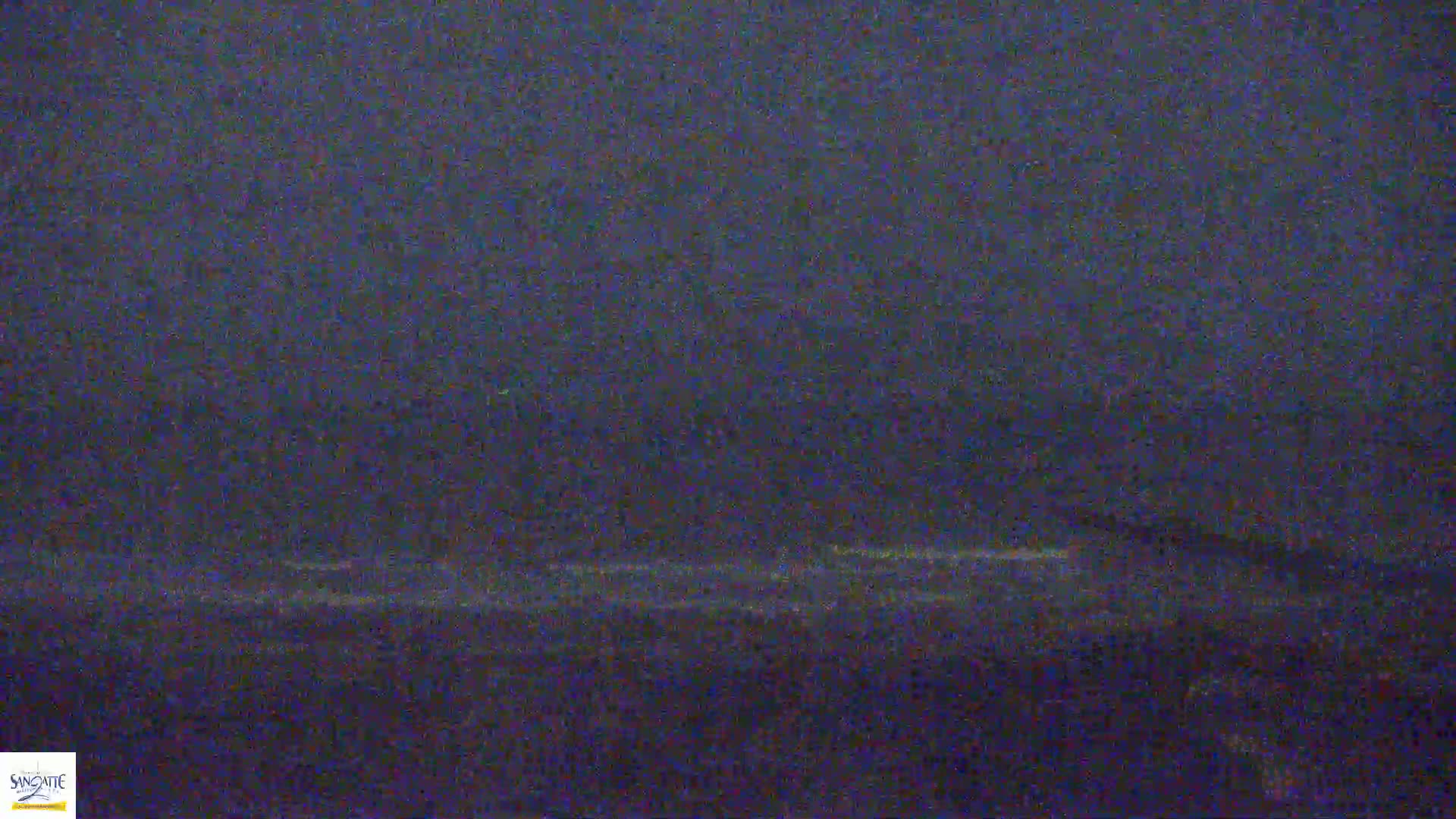 A dark, blurry image shows a dimly lit body of water with a faint horizon line under an overcast sky.