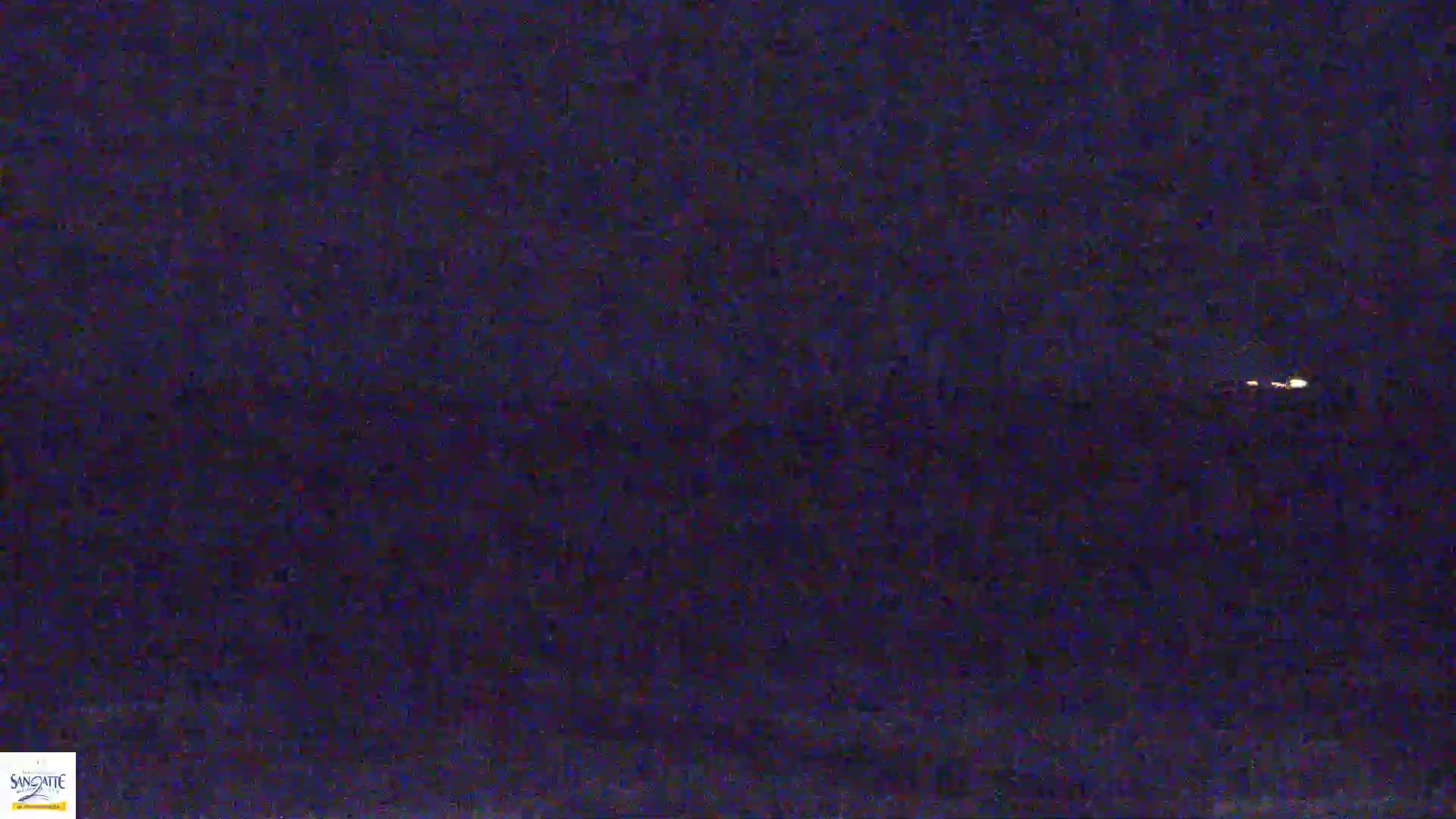 A nighttime view of a dark body of water with a few distant lights visible on the horizon.
