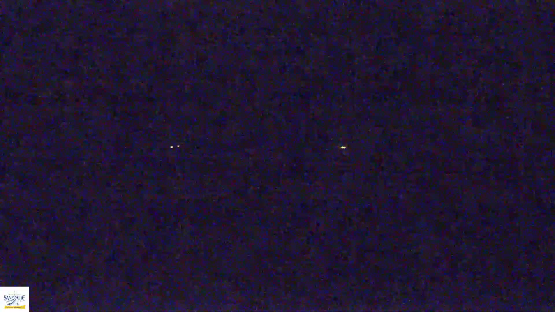 A dark, nighttime scene shows three small, faint lights in the distance.