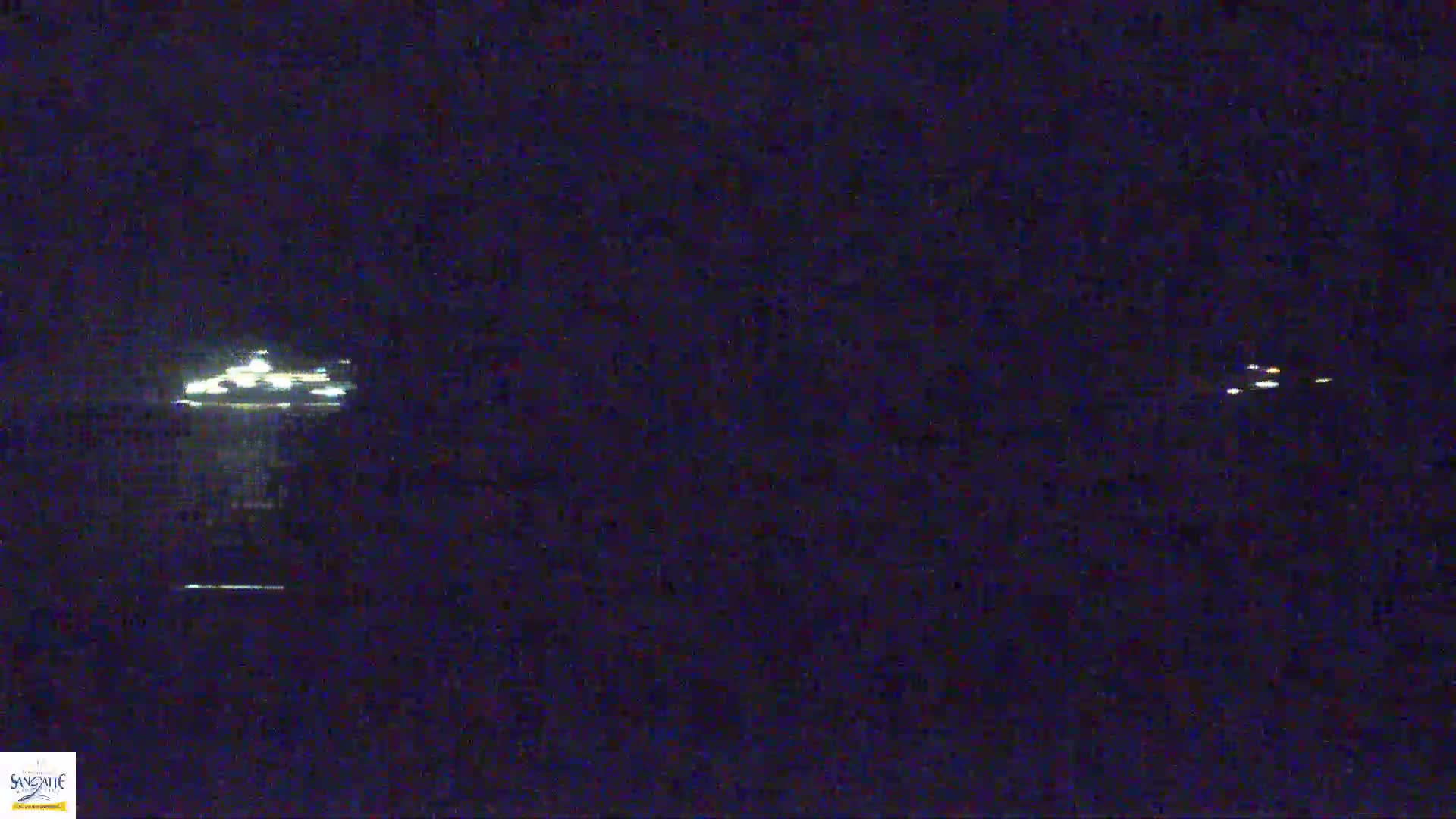 At night, two sets of distant lights are visible on a dark body of water.