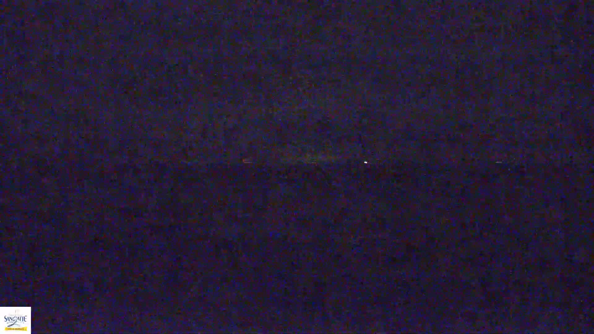 A dark, nighttime scene shows a distant horizon line with a few faint lights.