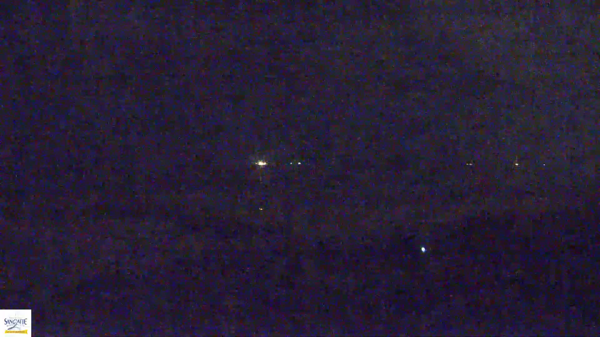 A nighttime outdoor scene shows a few distant lights in a dark, possibly cloudy sky.