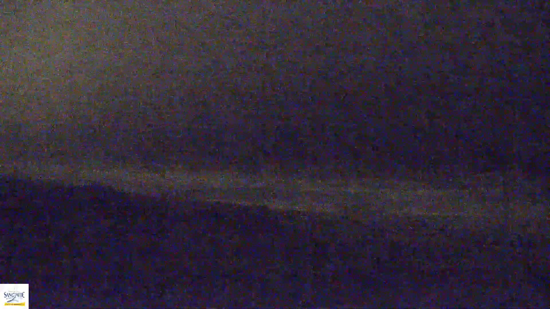 A blurry, dark image shows a low horizon line with a slightly lighter, hazy band above it, suggesting nighttime or low-light conditions.