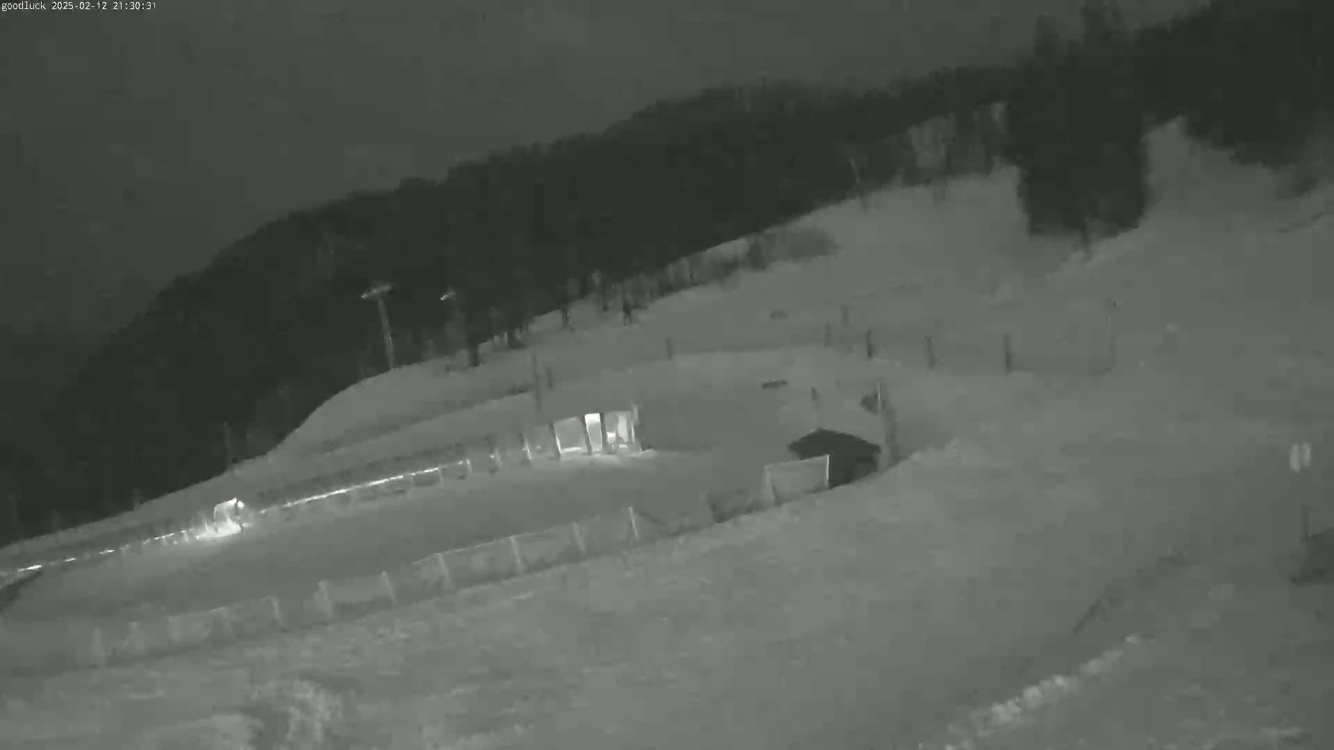 A nighttime, snow-covered ski slope is visible, with a few lights illuminating parts of the area.