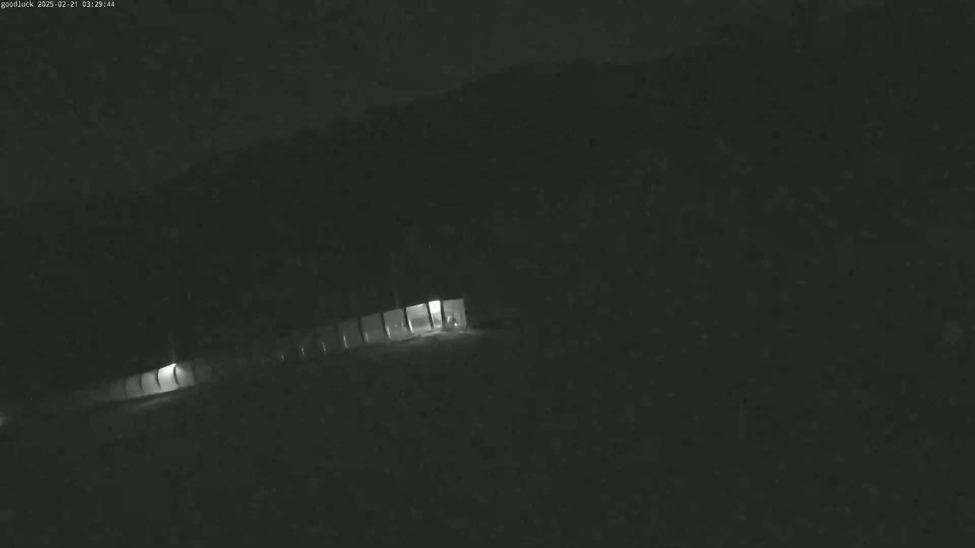 A dimly lit area at night, possibly a parking lot or road, is visible under a dark sky.