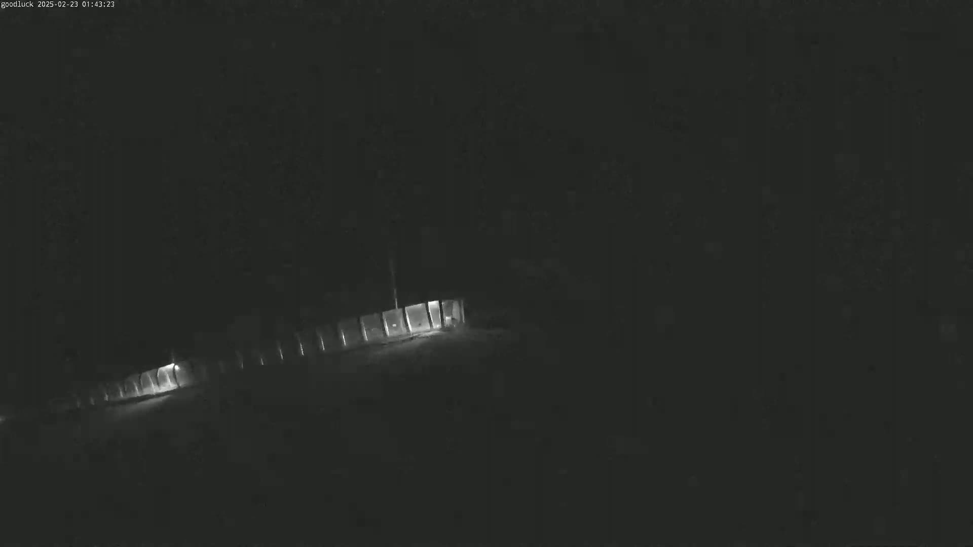 A long, low structure with illuminated windows is visible at night.
