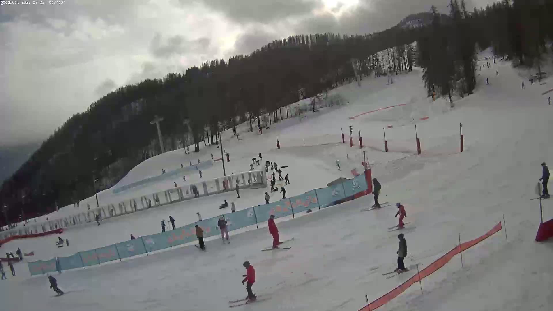 A ski slope with numerous skiers and snowboarders on a cloudy day.