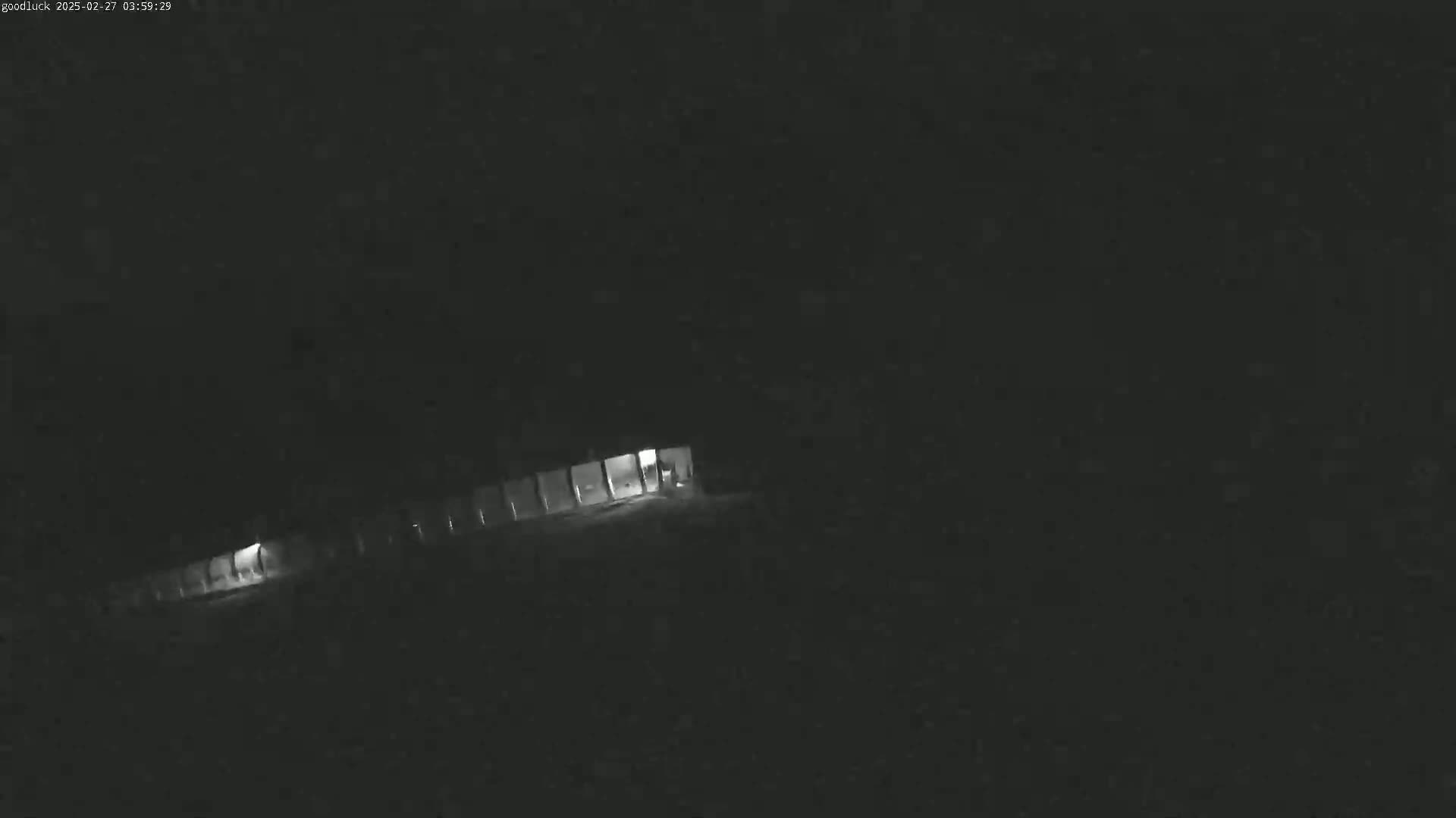 A dimly lit, long structure is visible at night under dark, possibly overcast conditions.