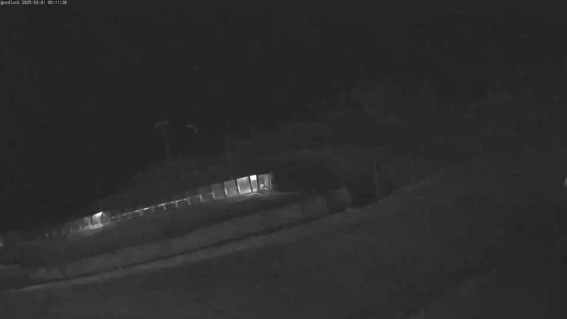A low-light nighttime image shows a dark road and a building with some interior lights illuminated.