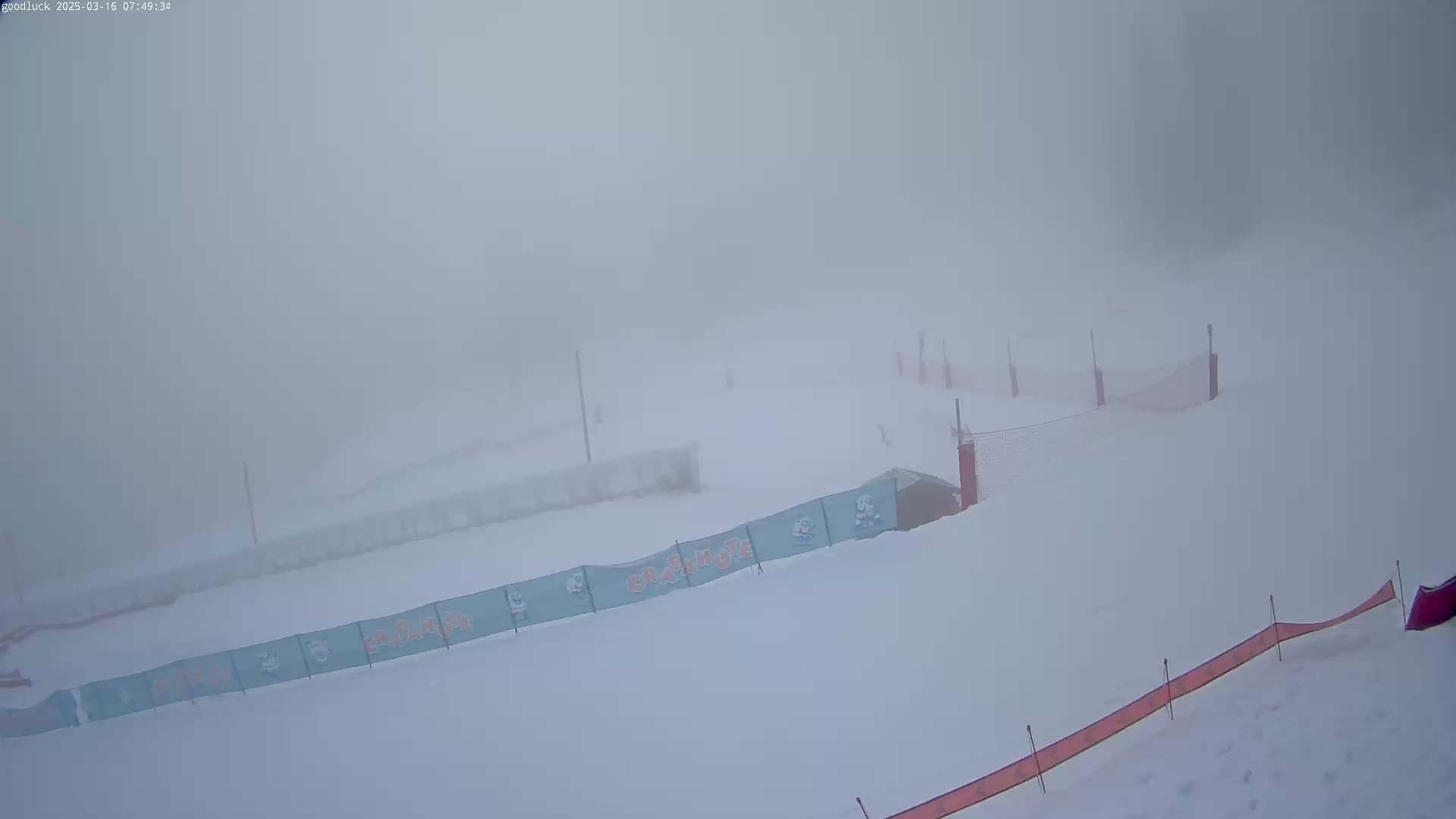 A snow-covered ski slope is obscured by heavy fog.