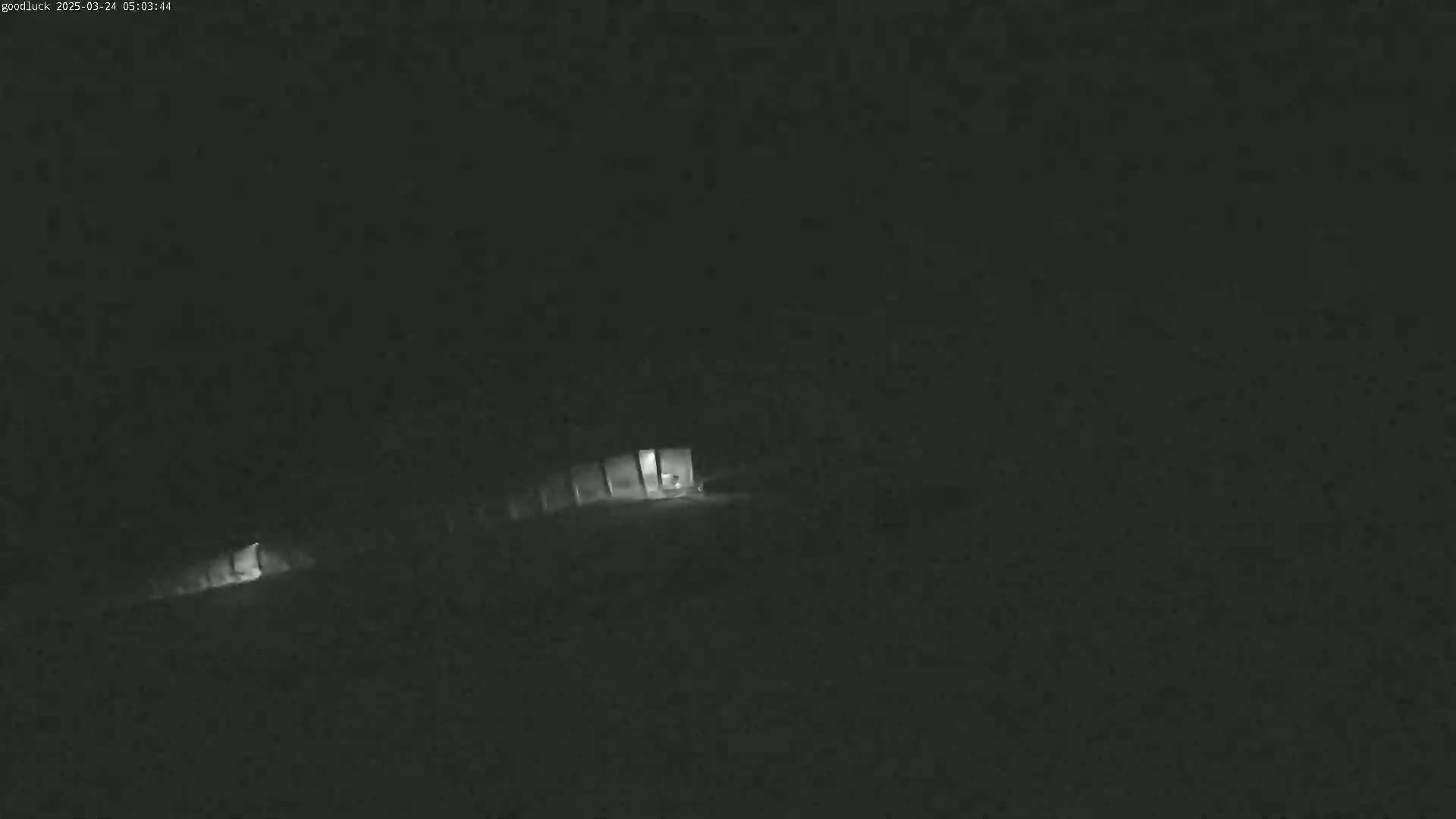 A dimly lit structure is visible in the dark, possibly at night.