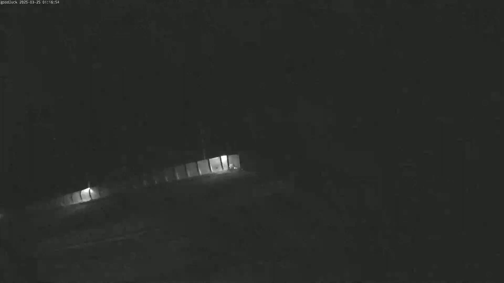 A dimly lit, long structure is visible at night in low-light conditions.