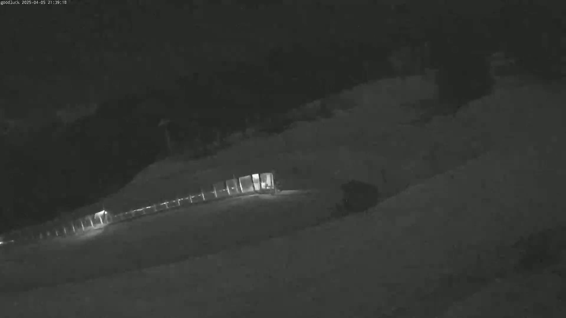 A dimly lit structure is visible at night in a snowy landscape.