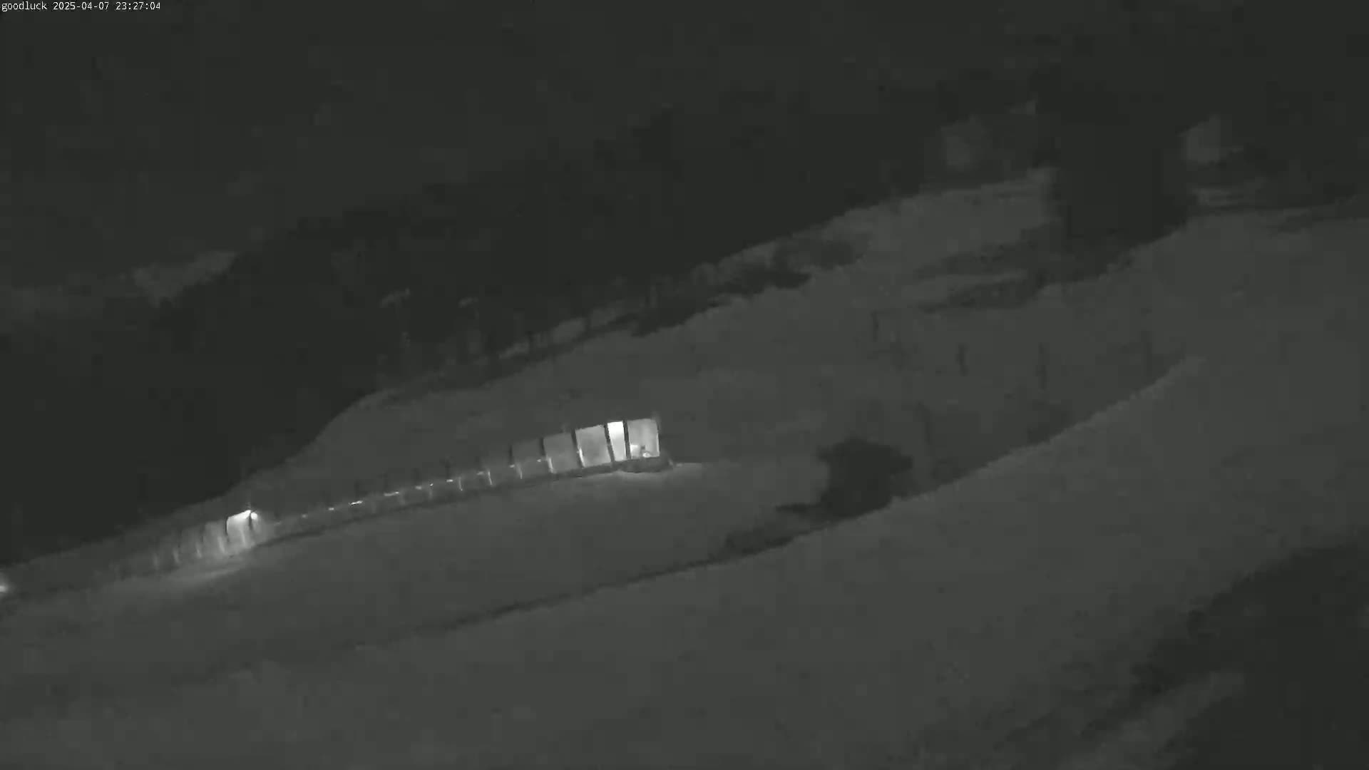 A snow-covered landscape is visible at night, illuminated by a few faint lights near a structure.