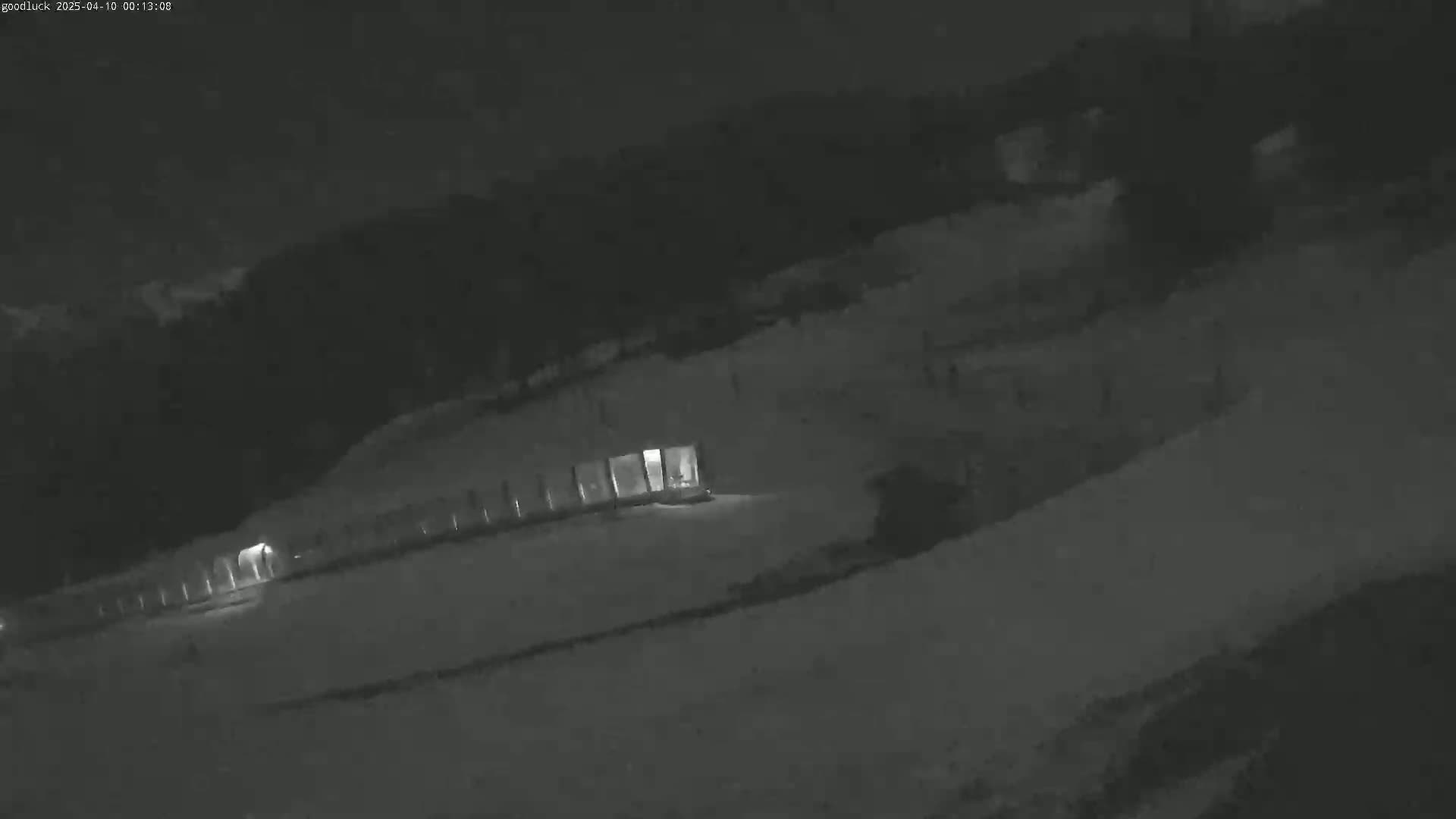 A long, low building with lit windows is partially visible in a snow-covered area at night.