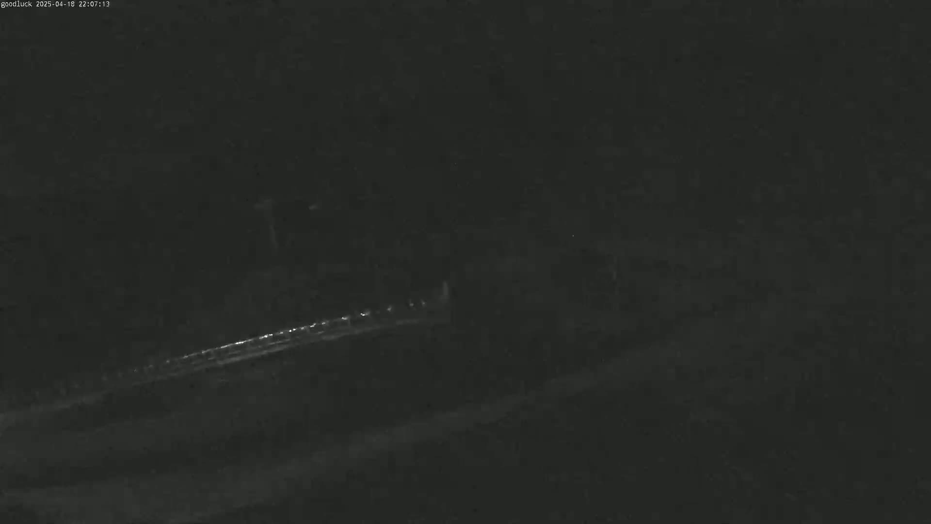 A dark, nighttime scene shows a faintly illuminated roadway with a few distant lights.