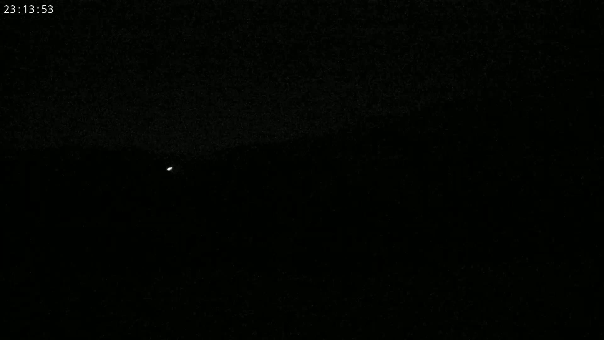 A single, small, bright light is visible in a dark, nighttime sky.