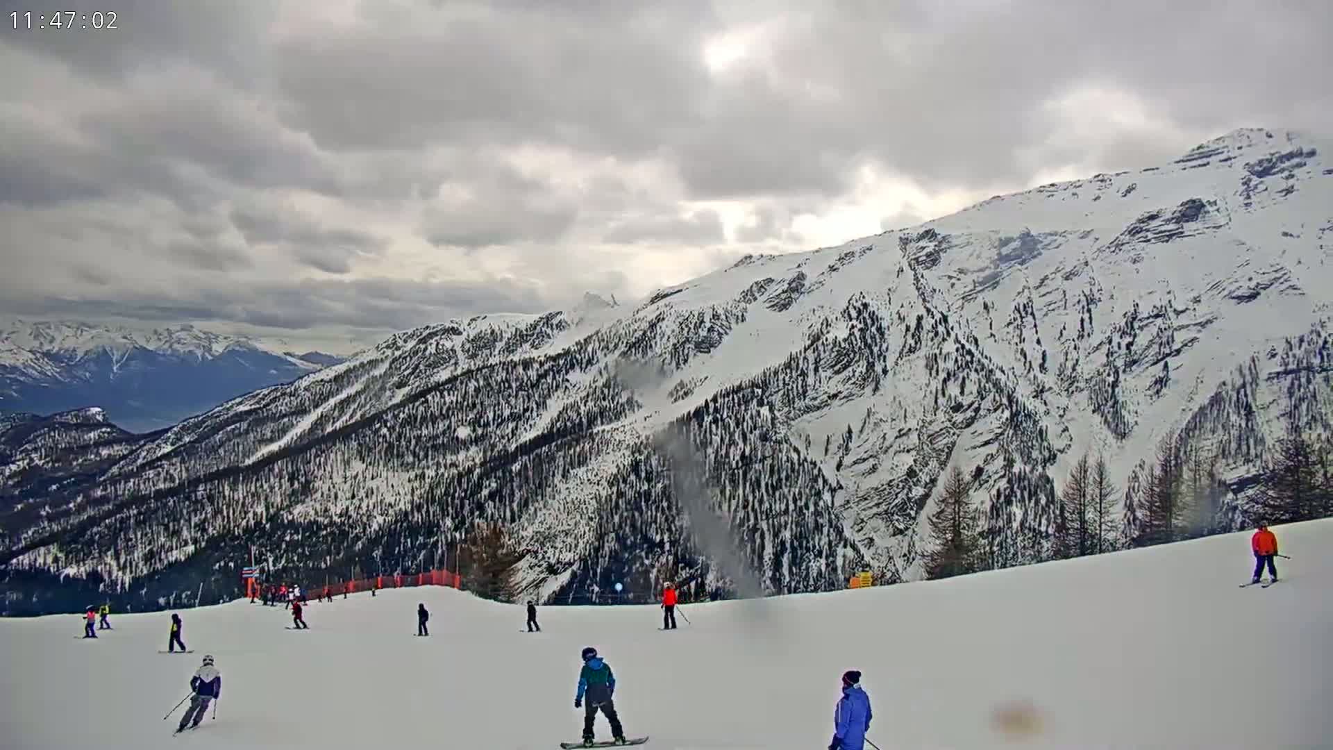 Several skiers and snowboarders are enjoying a snowy mountain slope under a cloudy sky.