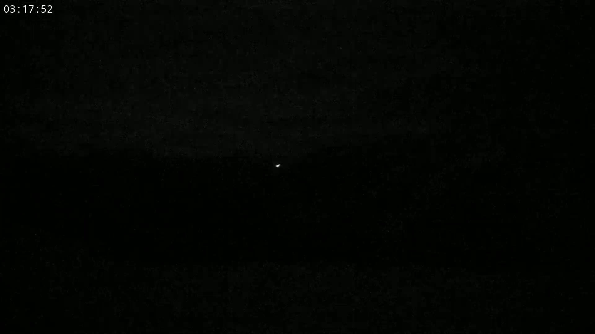 A single, faint light is visible in the dark night sky.