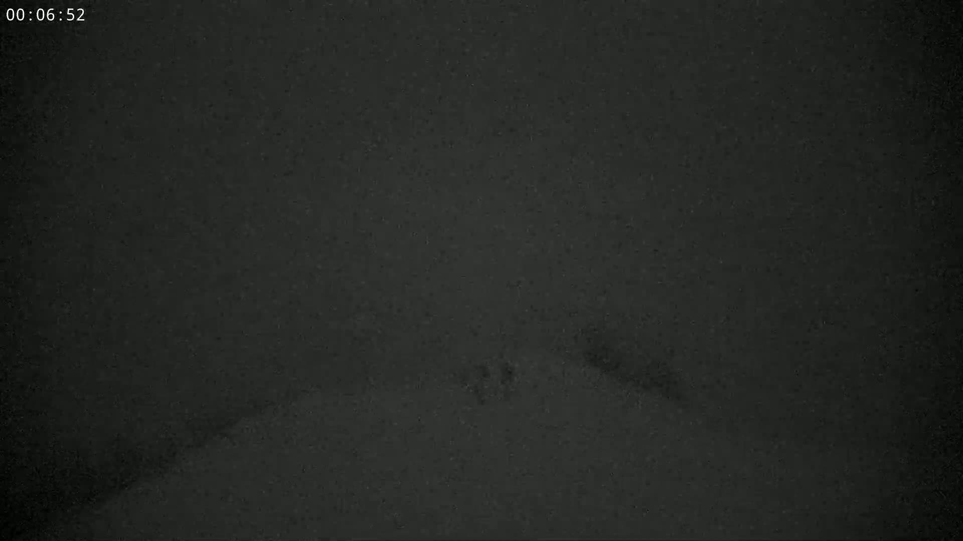 A dark, possibly nighttime scene shows a blurry, snow-covered ground.