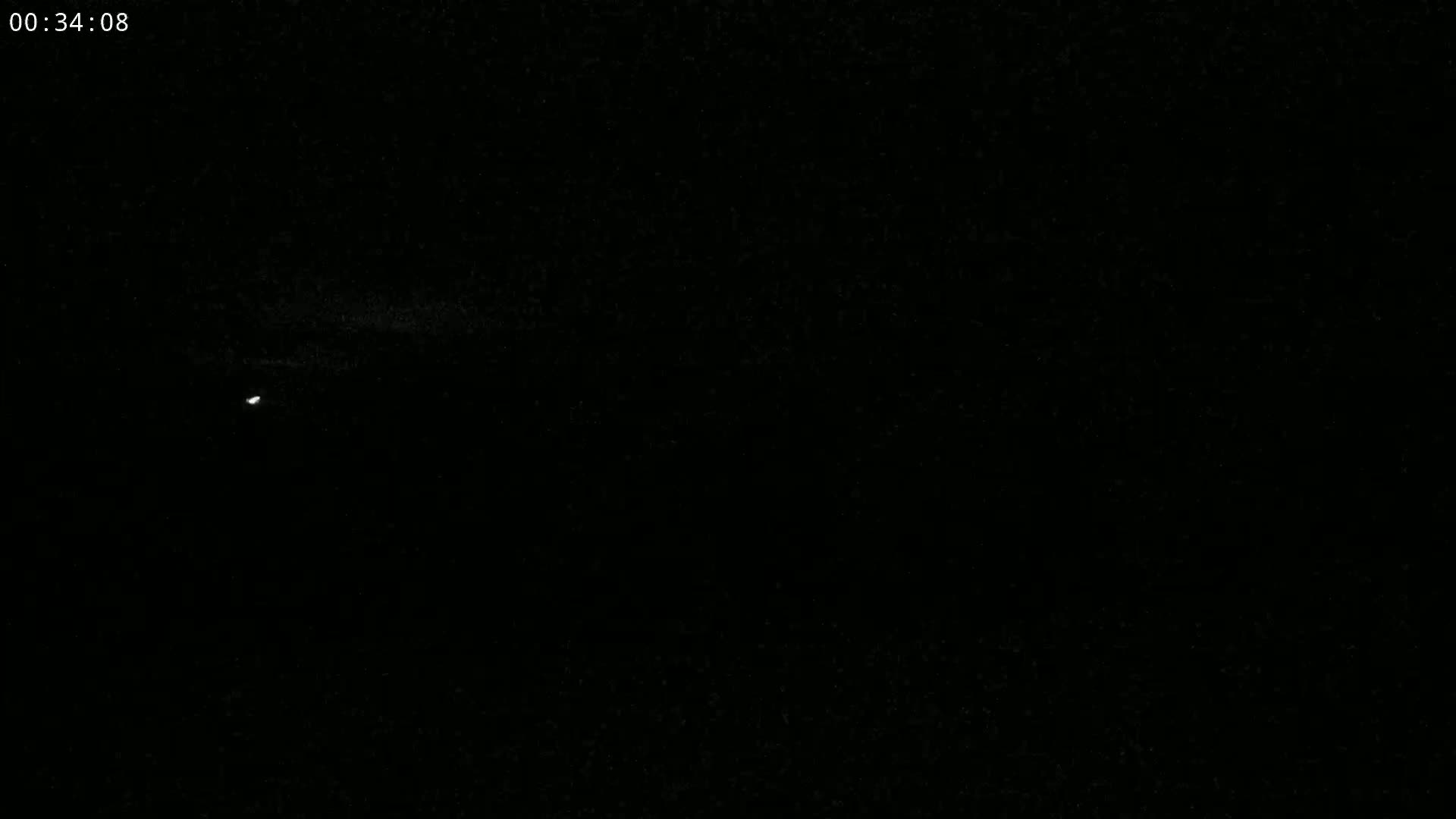 A single, small, bright light is visible in a dark, nighttime sky.