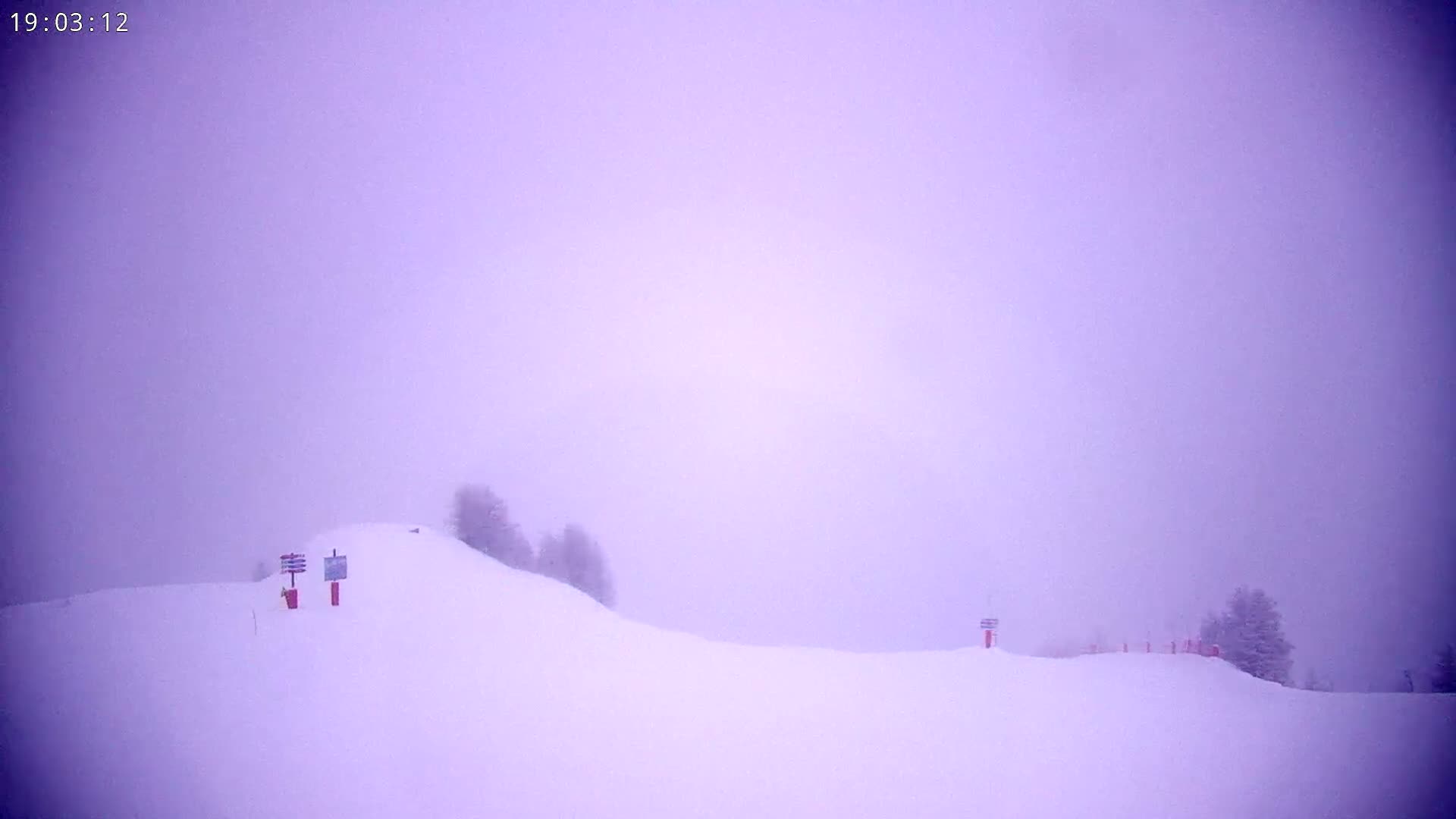 A snow-covered hill is shrouded in a thick, purplish fog.
