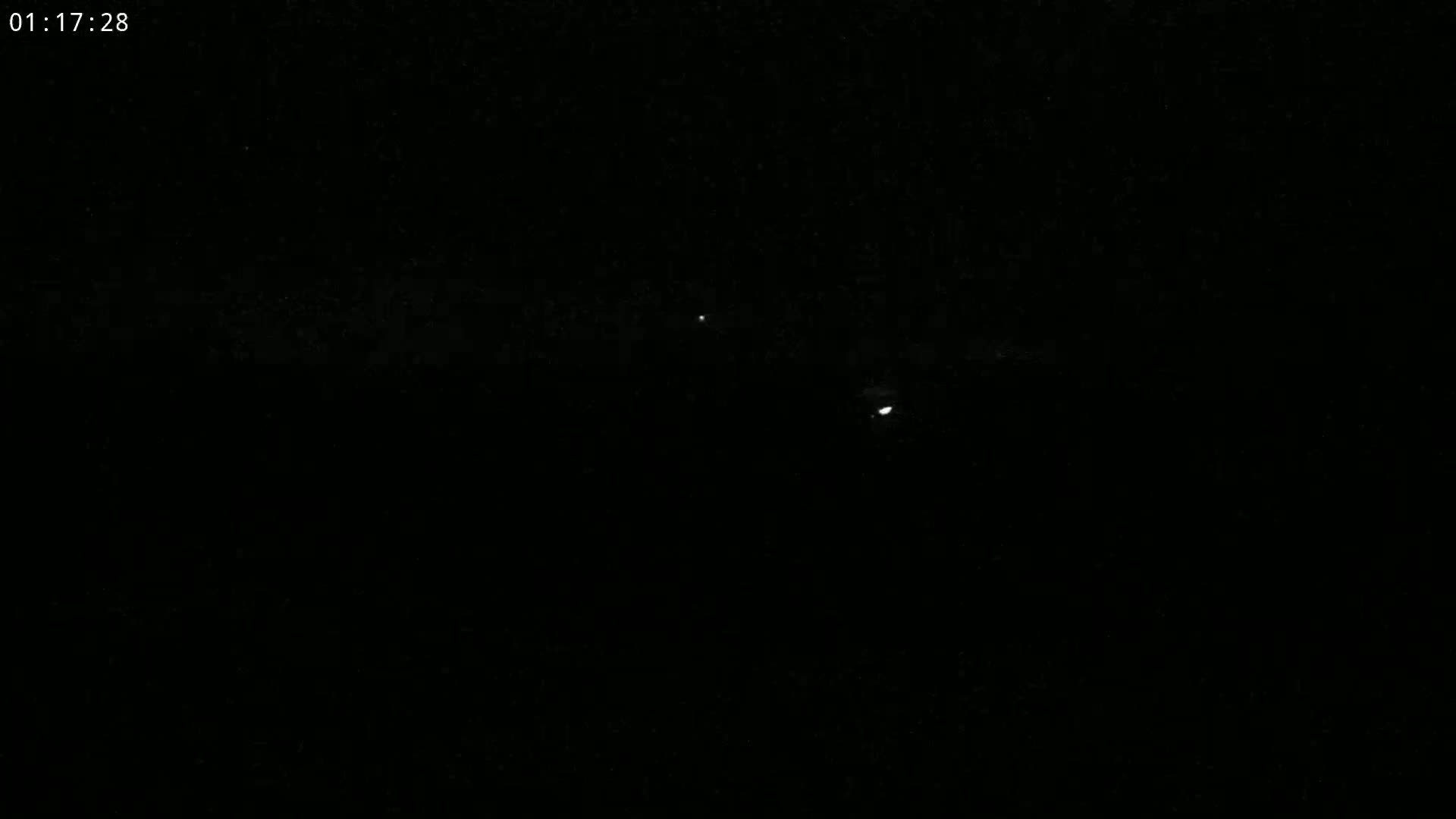 A dark nighttime scene with two faint lights visible in the distance.