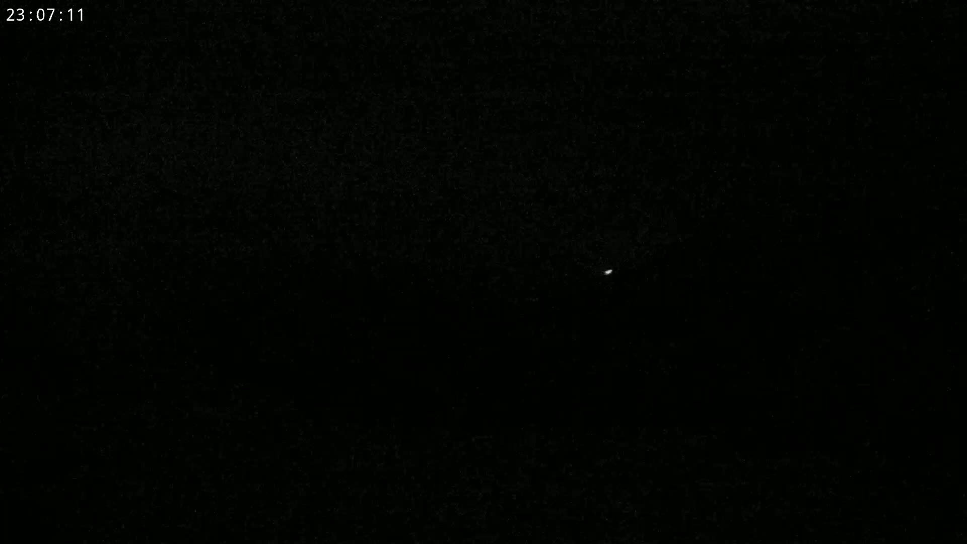 A single, small, bright light is visible in a dark, nighttime sky.