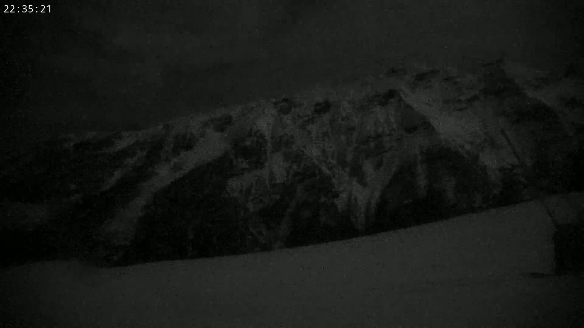 A dark, snow-covered mountainside is visible under a nighttime sky.