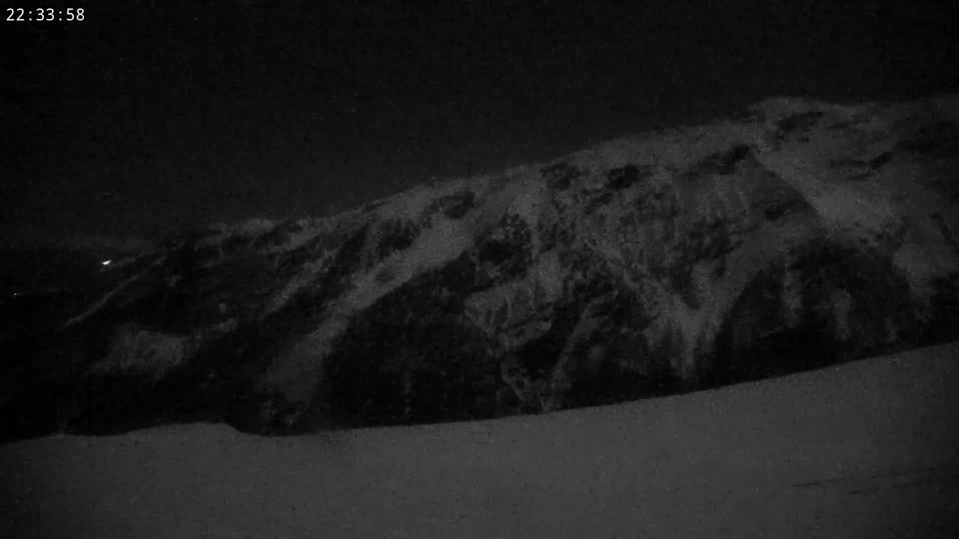 A snow-covered mountain is visible at night under a dark sky.