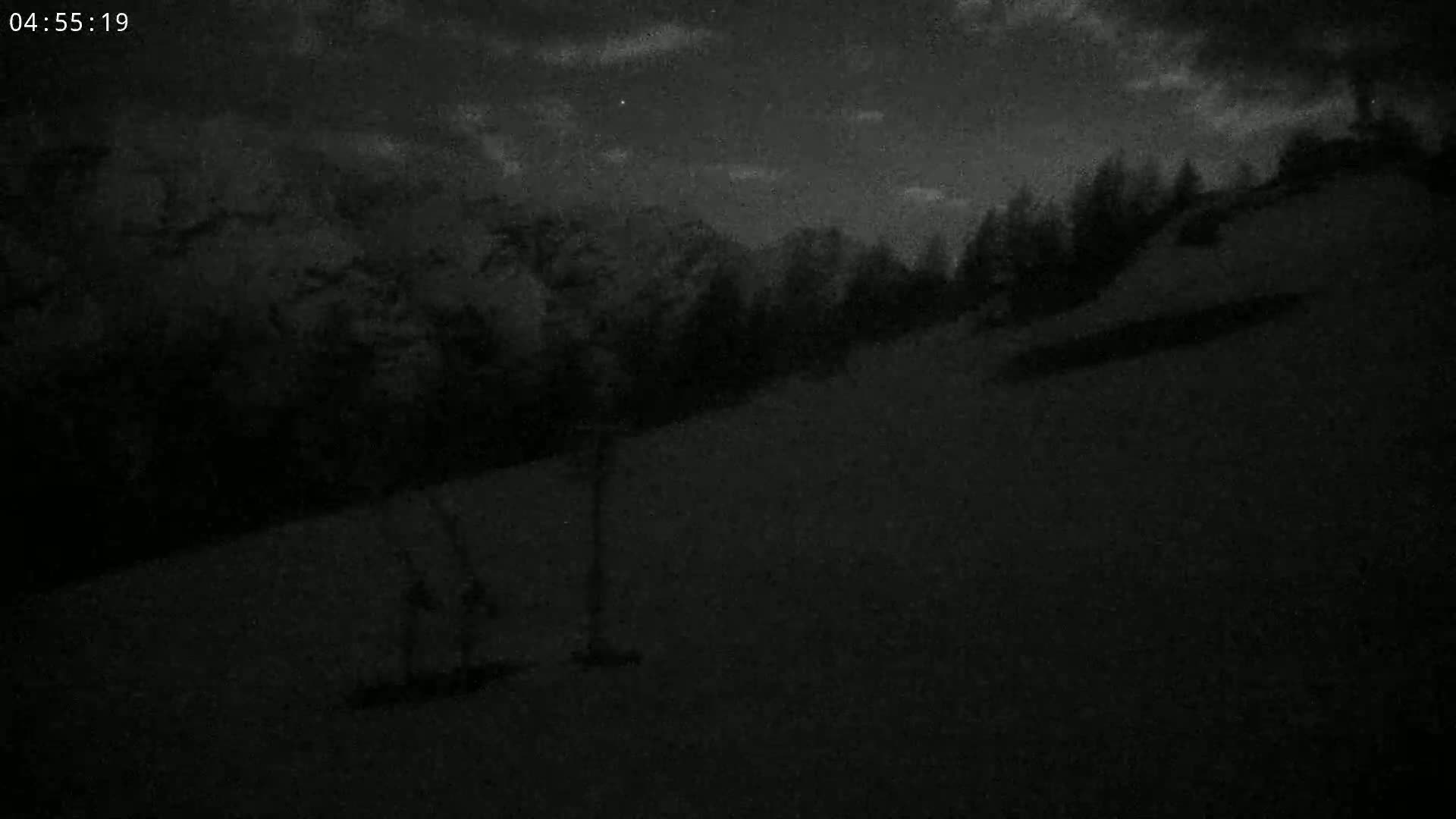 A dark, snowy landscape is visible under a night sky with some clouds.