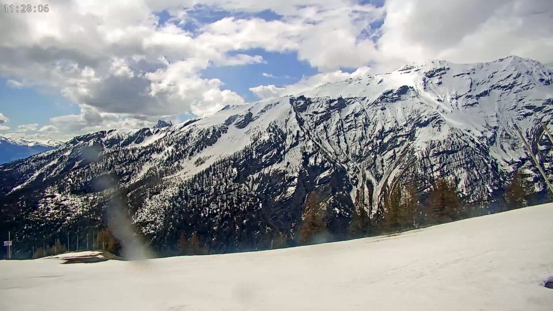 A snow-covered mountain range is visible under a partly cloudy sky.