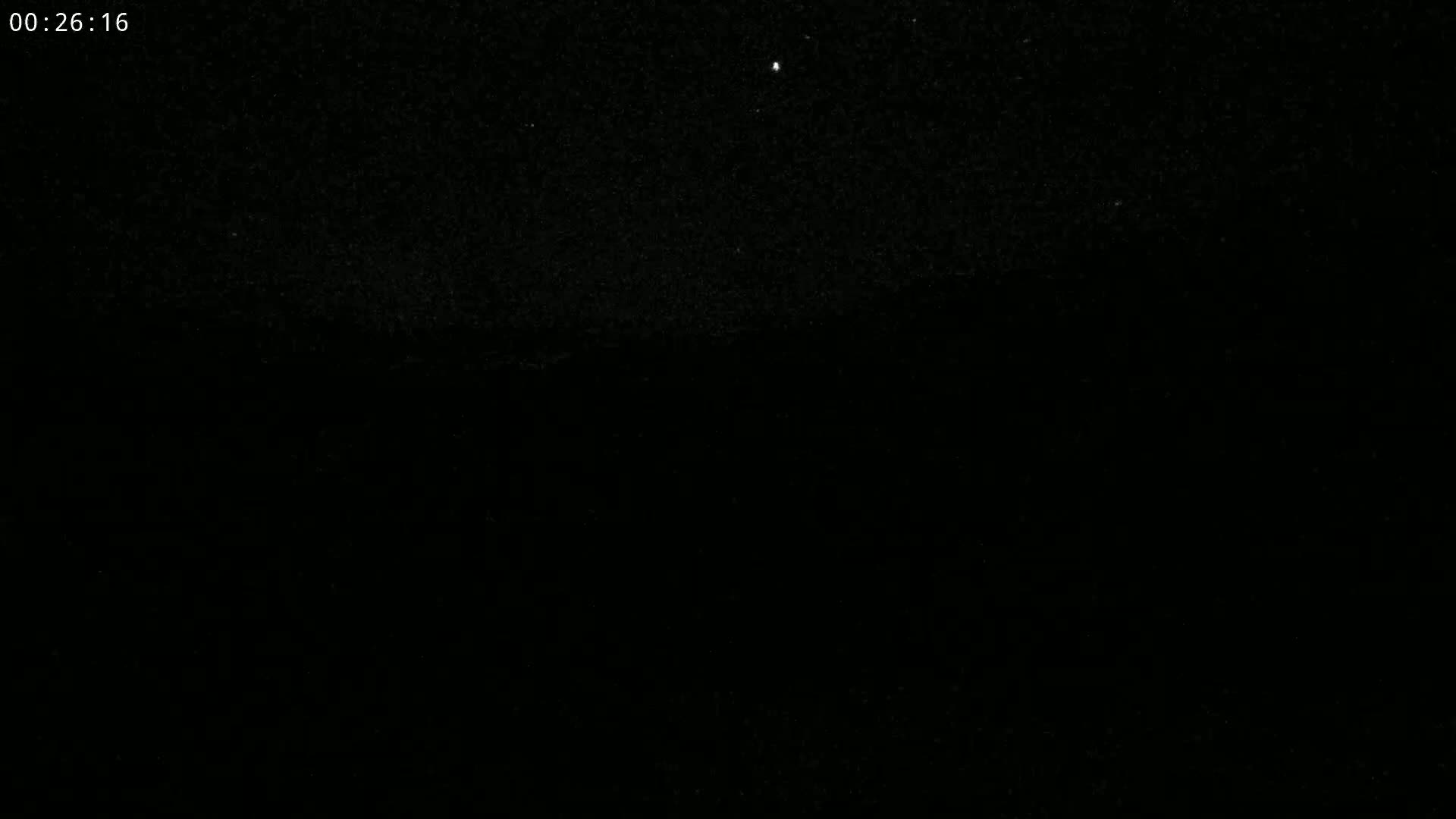 A dark, nighttime scene shows a few faint stars in the sky above a mostly black landscape.