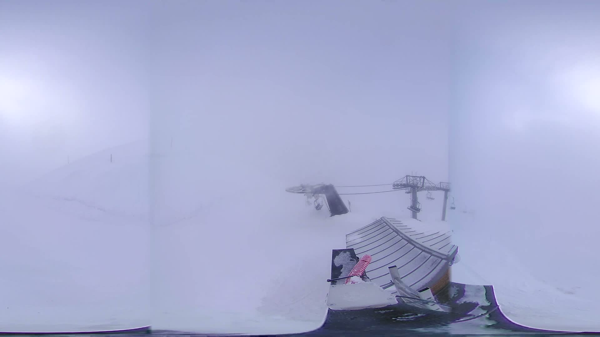 A snow-covered ski lift and surrounding landscape are shrouded in thick fog.