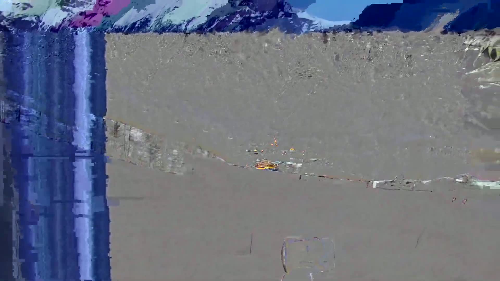 A long, blue vertical streak is next to a gray, mountainous landscape under a sunny sky.