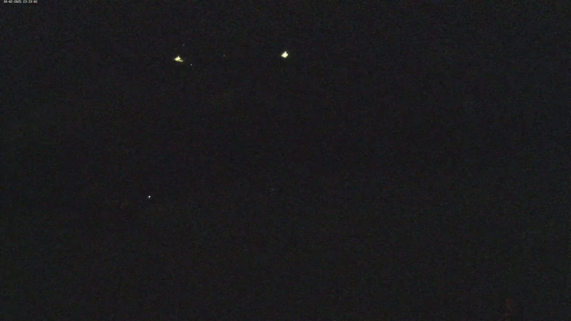 A dark nighttime scene shows a few faint lights in the distance.