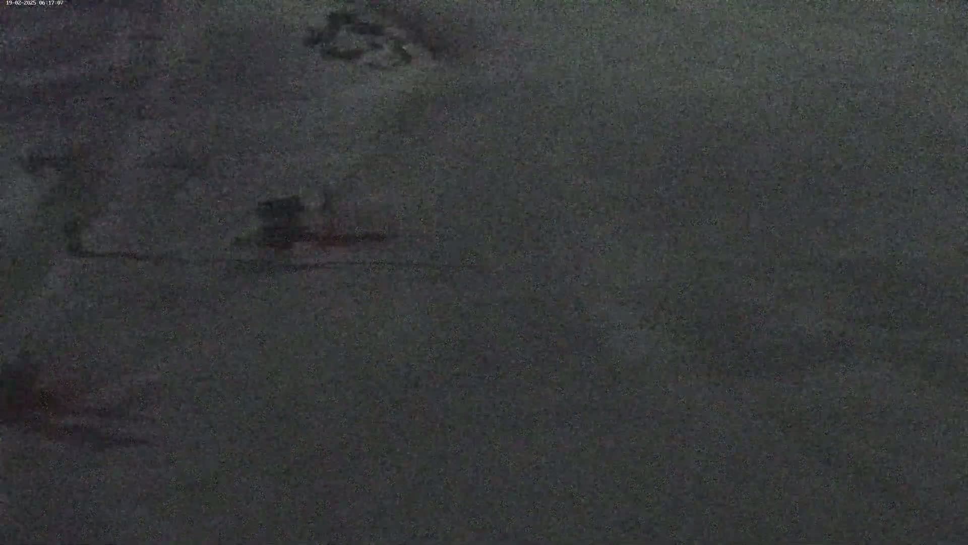A blurry, dark gray image shows an indistinct, possibly snowy or icy, ground.