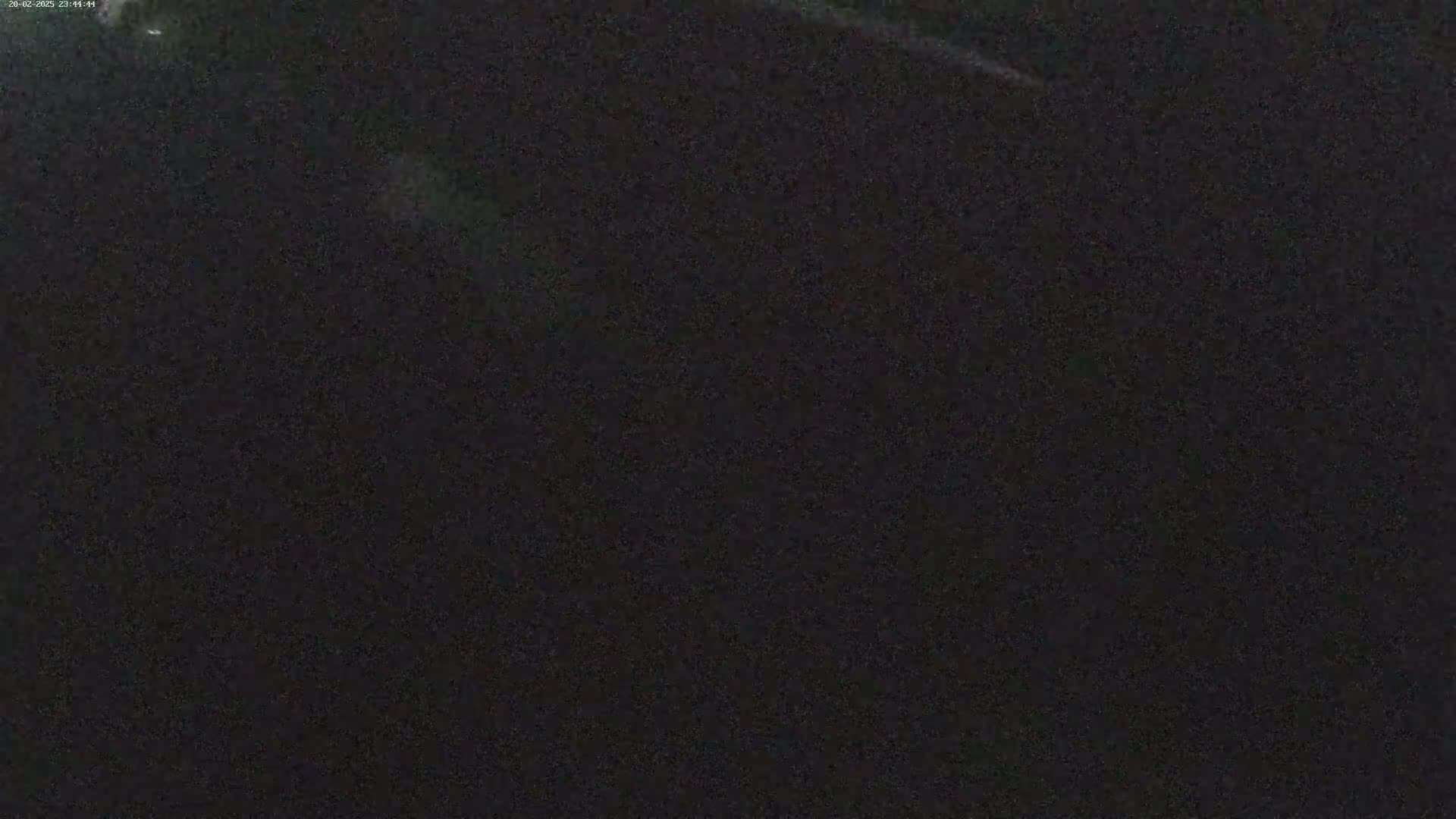 A nighttime image shows a dark, mostly featureless expanse with a few faint, light streaks.