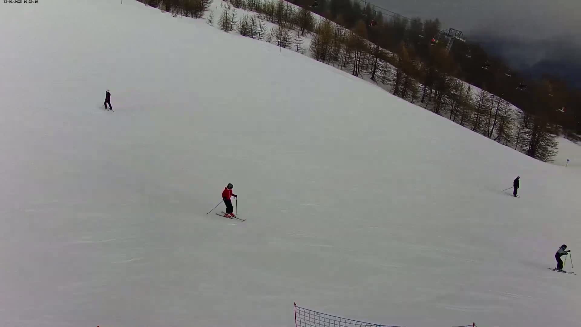 Several skiers are on a snow-covered slope under an overcast sky.
