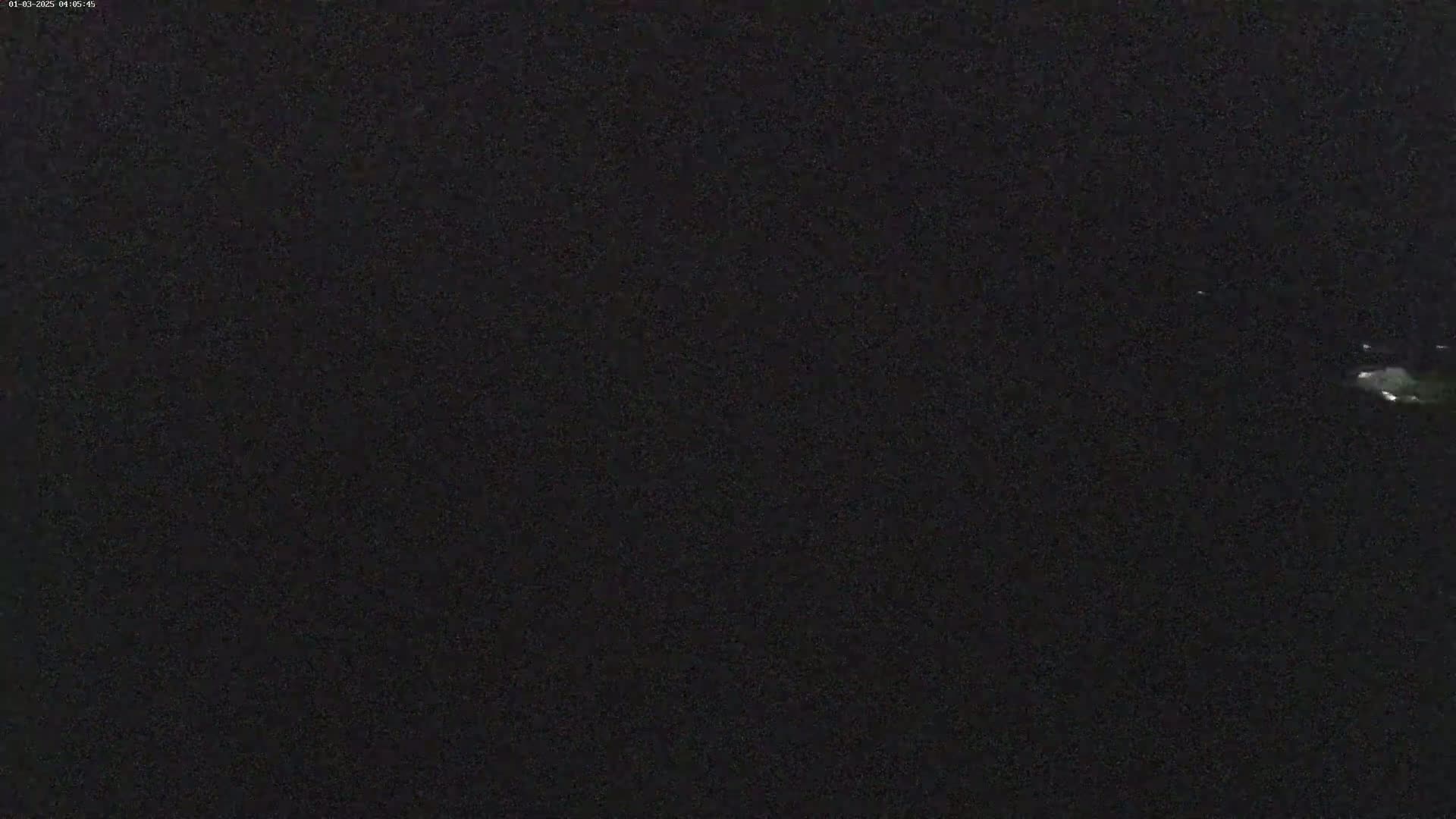 A nighttime image shows a dark, possibly overcast sky with a few faint lights visible in the distance.
