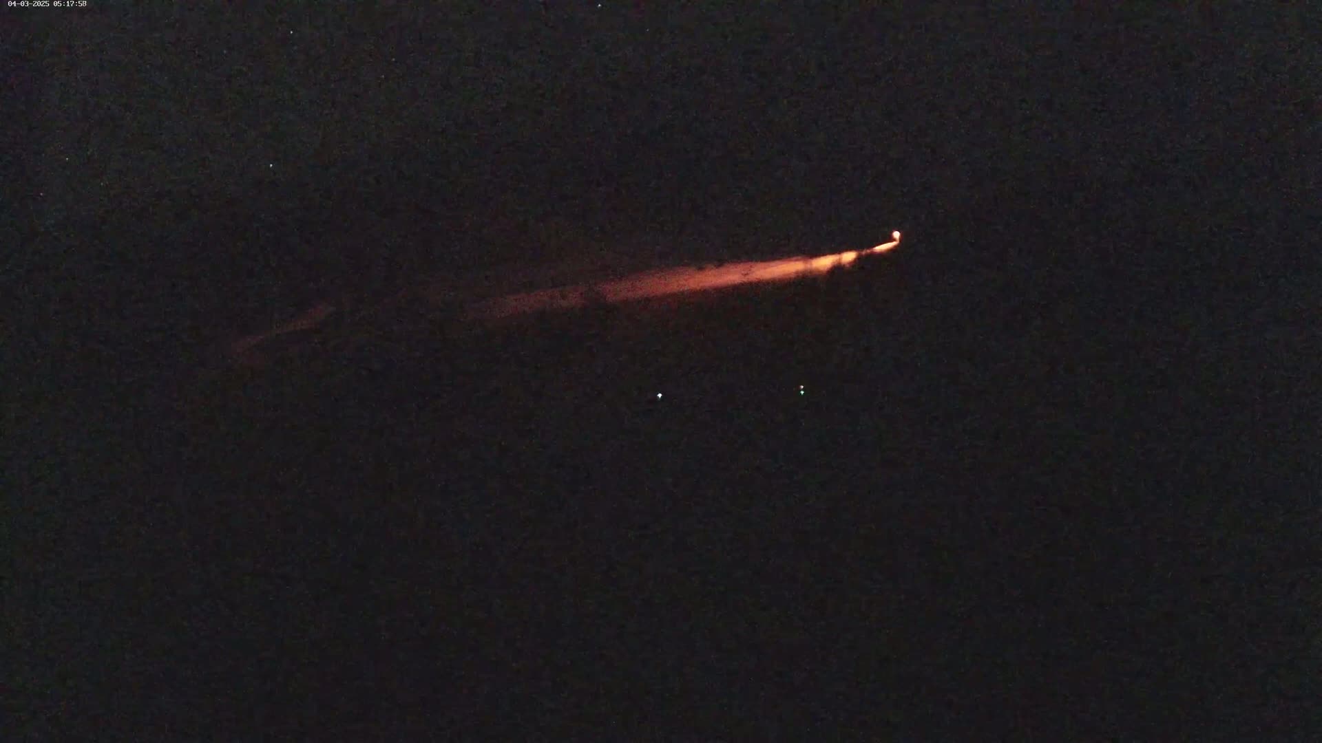 A long, low orange light stretches across a dark, nighttime sky.