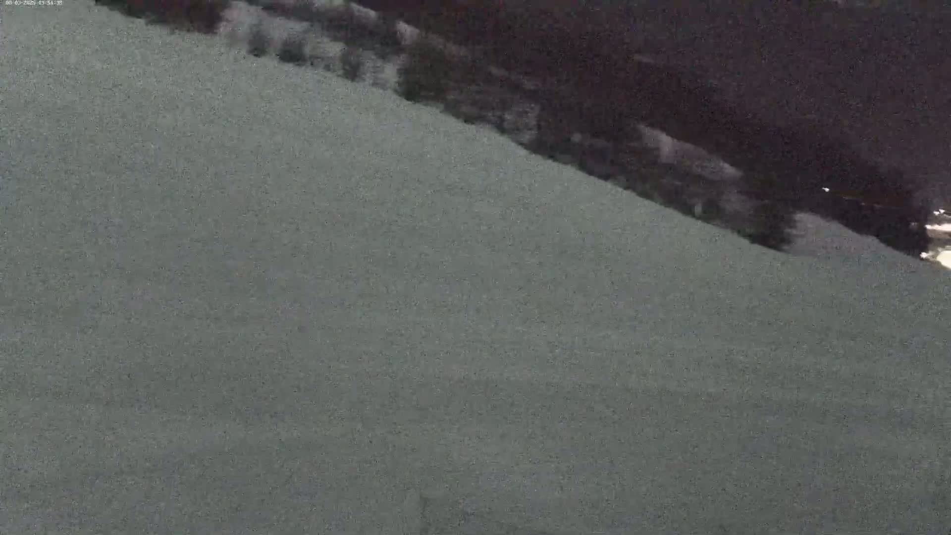 A snow-covered slope descends into a dark, possibly nighttime, background.